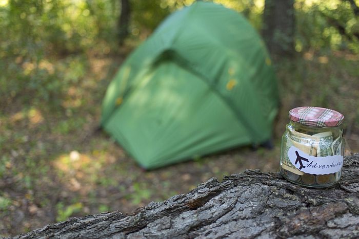 money jar on a log with tent in the background