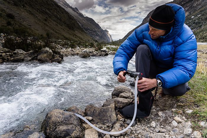 backpacker using a water filter