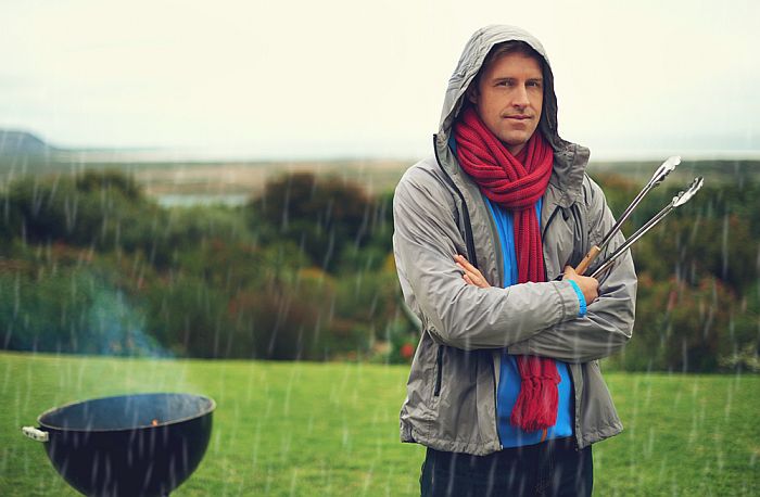 A man grilling in the rain